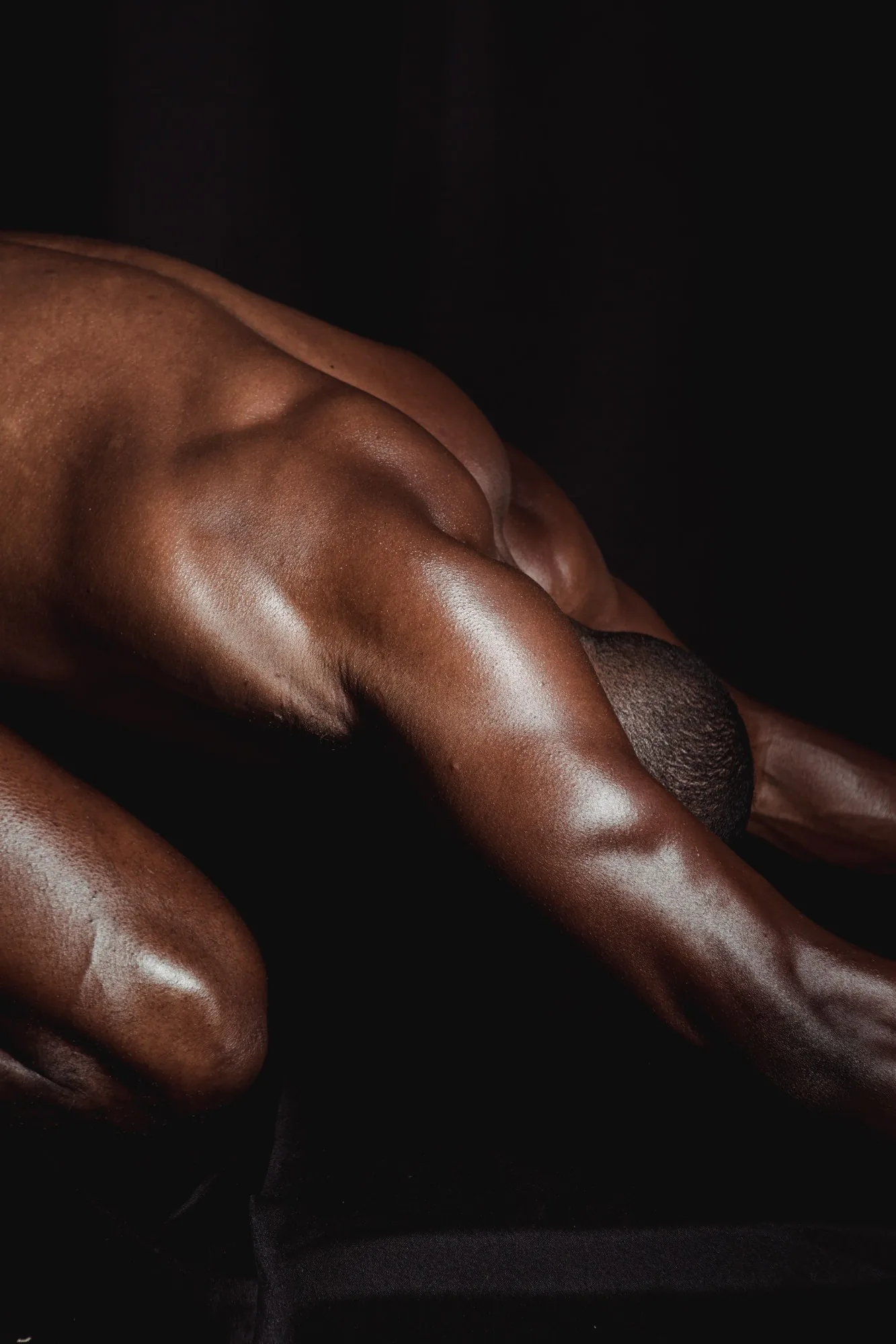 Warm light on the oiled back and shoulder of a man during a massage